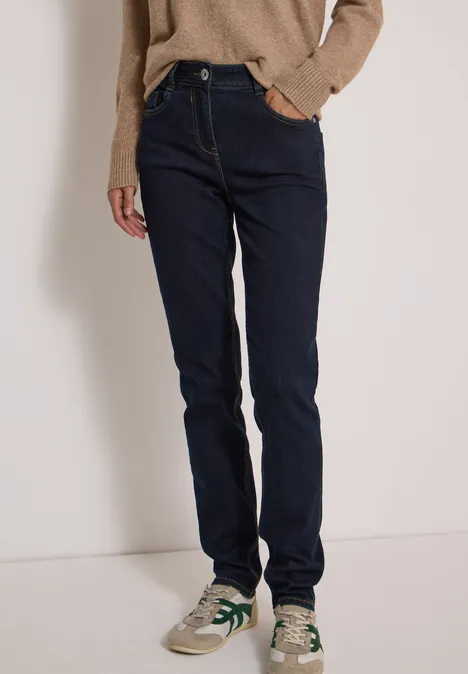 High Waist Slim Leg Jeans Slim Fit rinsed wash Person trägt dunkelblaue Jeans, beigen Sneaker und braunen Pullover in schlichtem Stil.