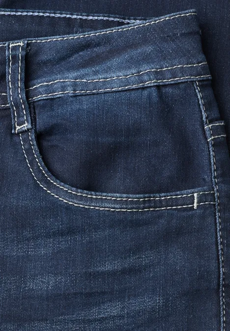 Close-up van een donkerblauw spijkerbroekzakje met witte contrasterende stiksels.