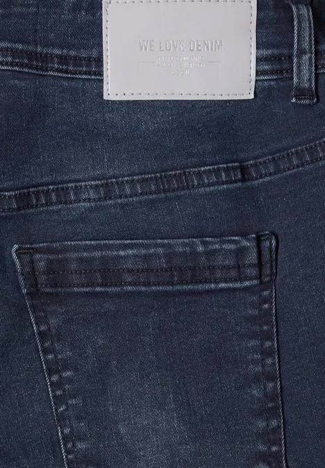 Donkerblauwe spijkerbroek met achterzak en licht lederen label in de taille.