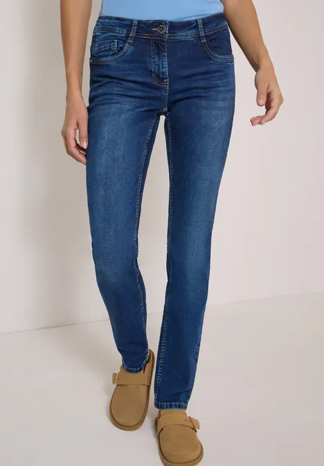 Dopasowane jeansy damskie slim w ciemnoniebieskim kolorze z brązowymi mokasynami.