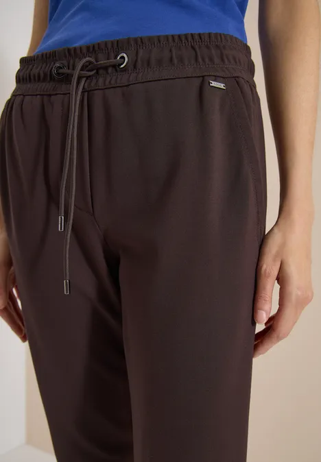 Donkerbruine joggingbroek met elastische band, trekkoord en zijzakken, gecombineerd met een blauw bovenstuk.