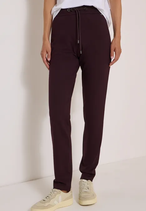 Pantalon de jogging bordeaux avec cordon, t-shirt blanc et baskets claires.