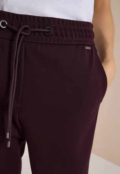 Pantalon de jogging bordeaux avec ceinture élastique, cordon de serrage et poches latérales.