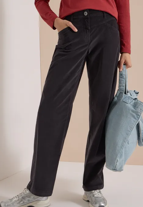 Noir pantalon droit, haut rouge à manches longues, baskets argentées et sac en tissu bleu clair.