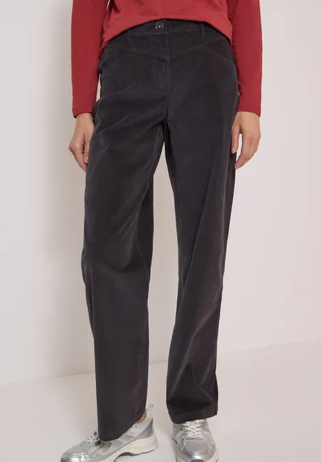 Pantalon droit en velours côtelé noir, taille haute, associé à un haut rouge et des baskets blanches.