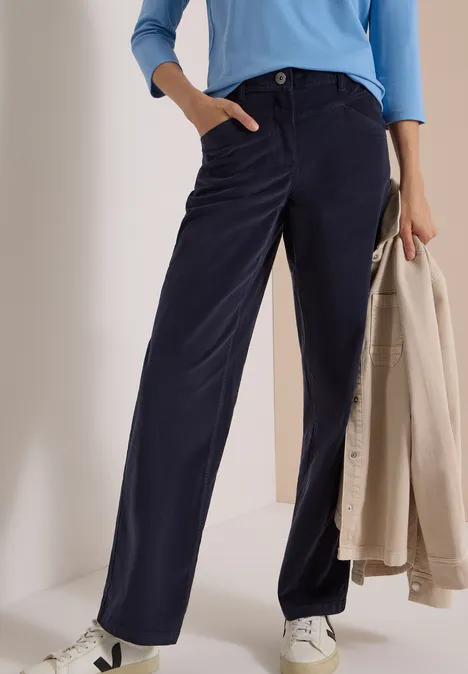 Pantalon large en velours côtelé bleu foncé, poches latérales, porté avec un haut bleu clair et des baskets blanches.