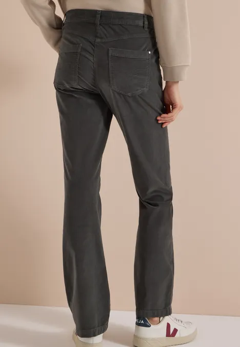 Personne de dos portant un jean gris foncé droit et des baskets blanches.