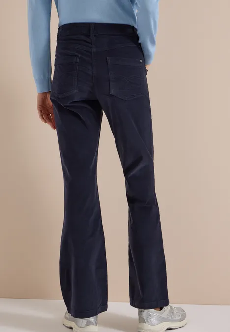 Vue arrière d'une personne en haut à manches longues bleu clair et pantalon évasé bleu foncé.