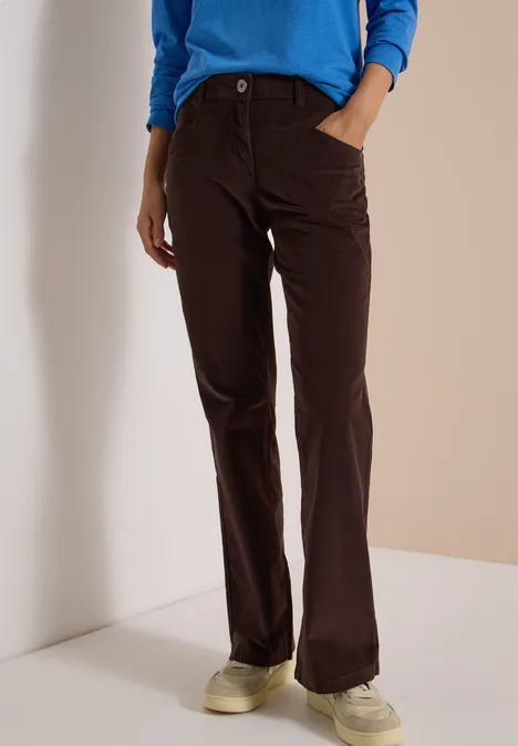 High Waist Bootcut Hose im Slim Fit truffle brown Eine Person trägt braune Cordhose mit geradem Schnitt und beigen Sneakern vor hellem Hintergrund.