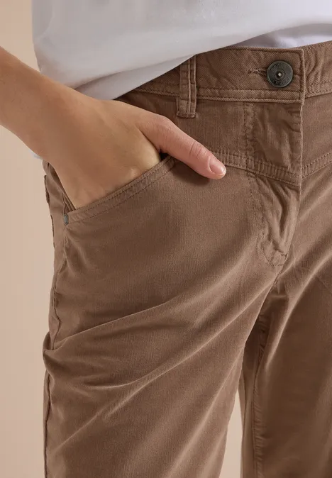 Gros plan d’un pantalon marron avec une main glissée dans la poche.