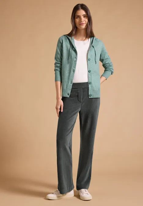 High Waist Straight Leg Hose w kroju Loose Fit easy khaki Kobieta ma na sobie biały t-shirt, turkusową bluzę z kapturem i luźne szare spodnie na neutralnym tle.