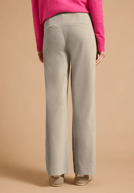 Spodnie z wysokim stanem i prostymi Straight Leg nogawkami o Loose Fit kroju silvery beige Osoba widziana od tyłu w beżowych szerokich spodniach, różowej bluzce i beżowych butach na jednolitym tle.