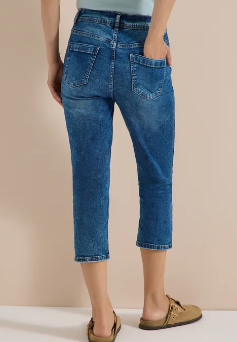 Frau trägt knöchellange, lockere blaue Jeans mit zwei Gesäßstaschen und umgeschlagenem Saum.