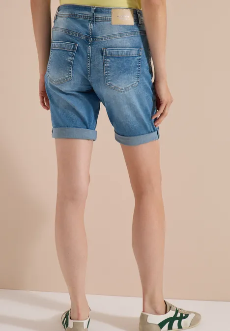 Short taille haute Slim Leg, coupe ajustée authentic used wash Femme de dos en short en jean retroussé, top jaune et baskets blanches.