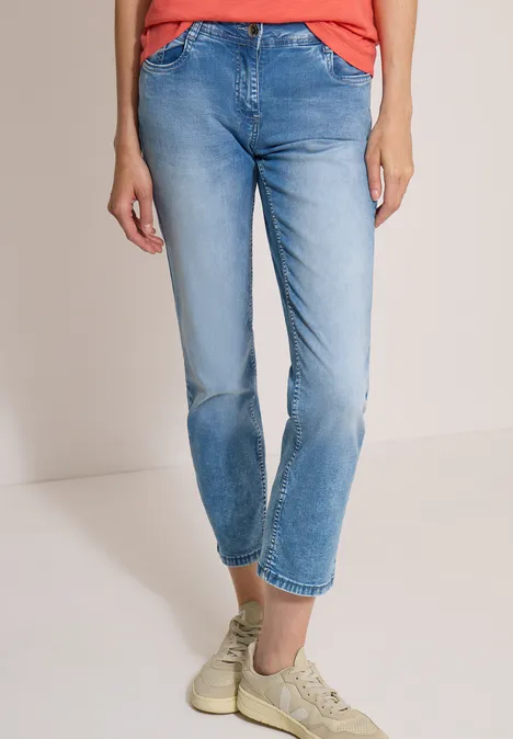 Jean taille mi-haute à coupe Straight Leg et coupe décontractée light blue wash Personne en jean bleu clair, haut rouge et baskets beiges, vue avant jusqu'aux chevilles.