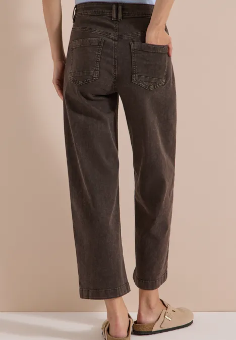 7/8 High Waist Jeans im Loose Fit brown cacao Eine Person trägt weite, dunkelbraune Jeans und beige Halbschuhe, Hände in den Gesäßtaschen.