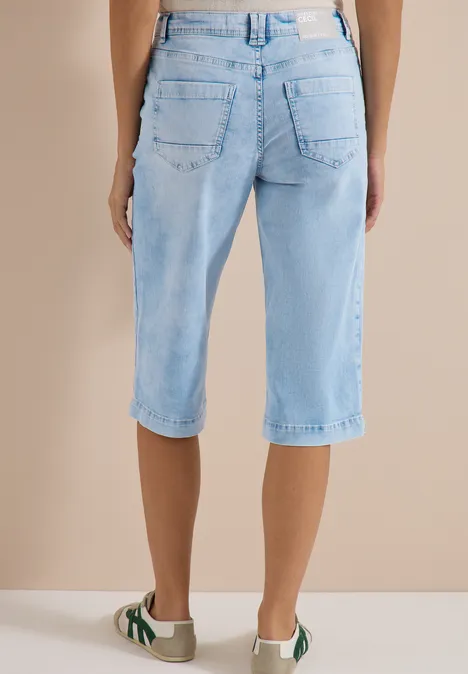 Wide Leg Capri Jeans im Loose Fit light blue random bleached Person von hinten in hellblauen Jeans-Caprihosen bis knapp unter die Knie und weißen Sneakern.