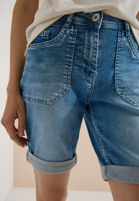 Detailaufnahme von blauen Jeans-Shorts mit umgeschlagenem Saum an Taille und Oberschenkeln.