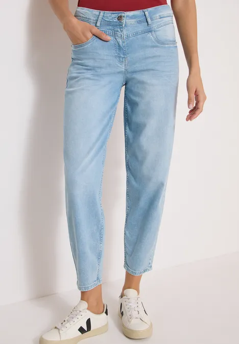 Eine Person trägt hellblaue, hoch taillierte Jeans mit geradem Bein und weiße Sneaker.