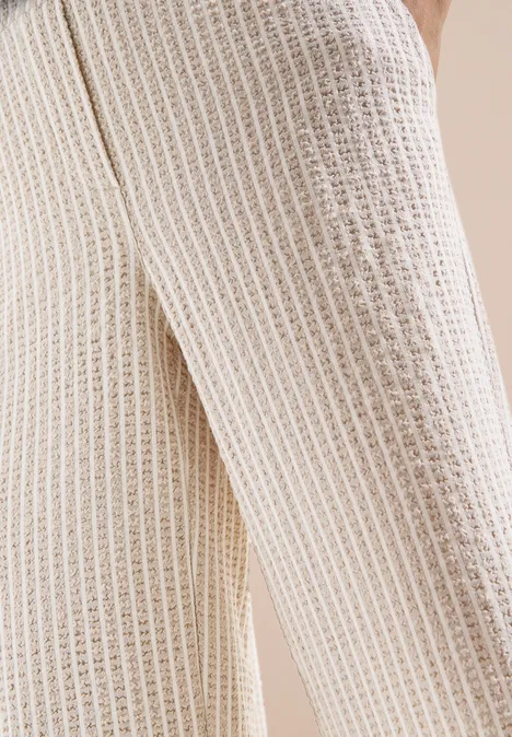 Pantalon large en qualité seersucker grain beige Gros plan d’un pantalon beige en maille gaufrée
