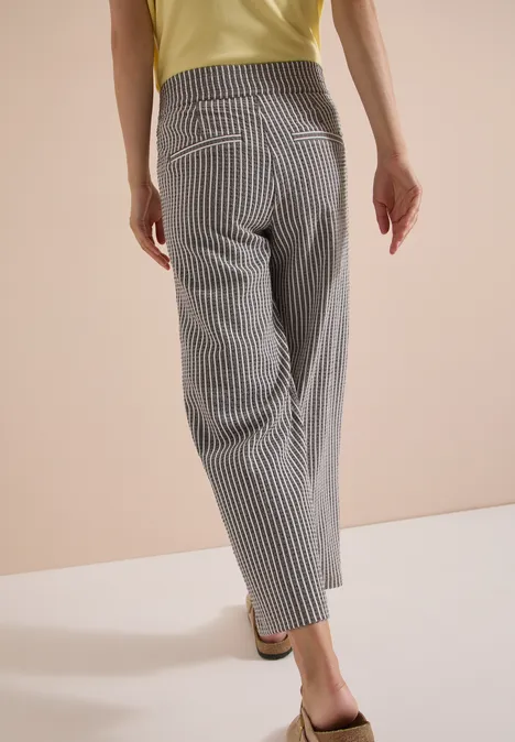 Personne vue de dos portant un pantalon ample à rayures verticales et un top jaune, style décontracté.