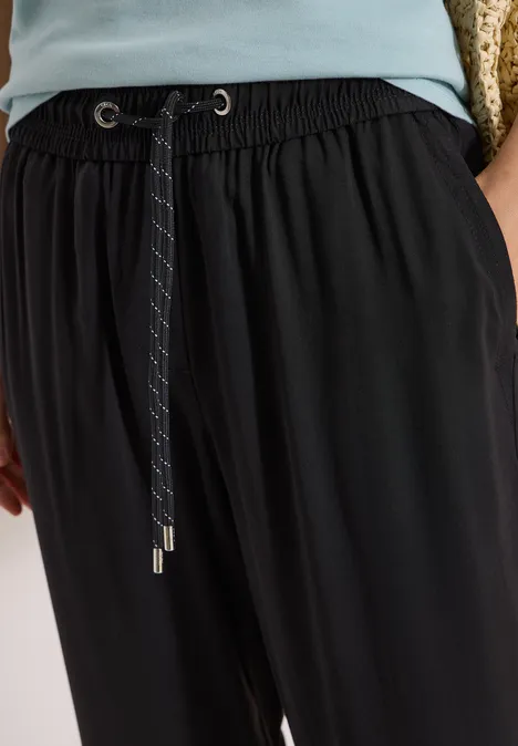 Schwarze Stoffhose mit Gummibund und Kordelzug, lässig geschnitten.