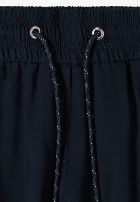 Pantalon Mid Waist Slim Leg en coupe loose universal blue Gros plan d'une ceinture de pantalon bleu marine élastique, cordon noir à pois blancs et œillets métalliques.