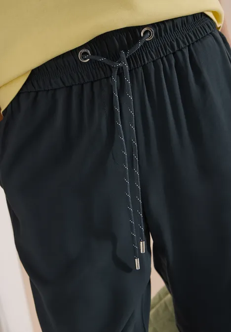 Schwarze Freizeit-Hose mit elastischem Bund und Kordelzug, detaillierte Naht und silberne Enden.