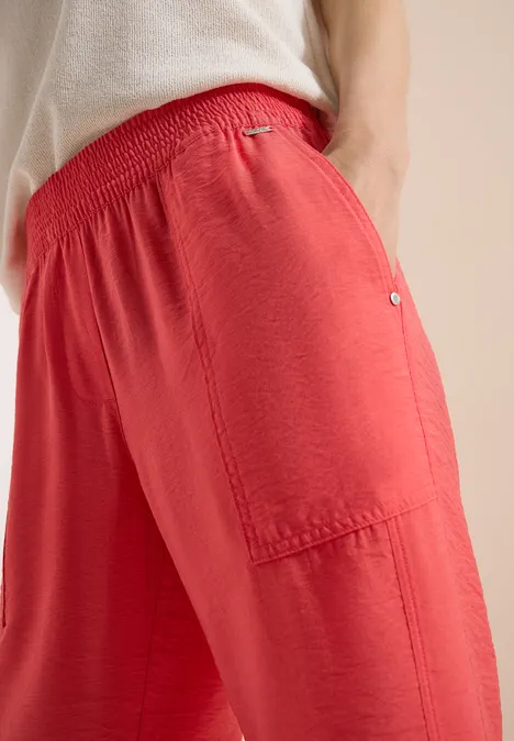 Mid Waist Slim Leg Hose im Loose Fit coral Locker sitzende, rote Stoffhose mit elastischem Bund und aufgesetzter Seitentasche, weich fallend.
