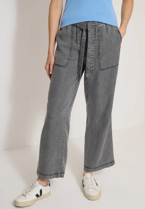 Pantalon à jambes larges avec ceinture à nouer mid grey random wash Jean gris coupe large avec poches plaquées, taille haute et baskets blanches.