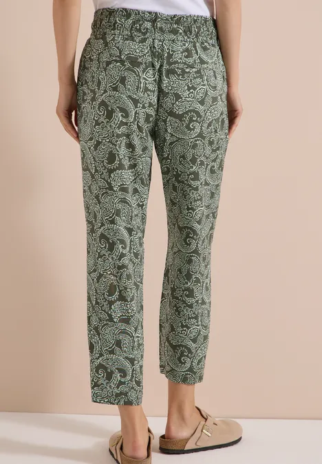 Grüne Stoffhose mit Paisley-Muster, lässiger Schnitt, getragen mit beigen Slippern.