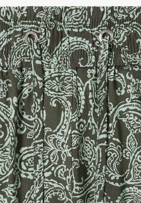 Nahaufnahme eines olivgrünen Stoffes mit hellblauem Paisley-Muster und Kordelzug in der Taille.