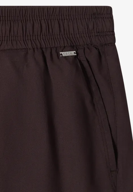 Nahaufnahme einer dunkelbraunen Hose mit Gummibund, Seitentasche und Metall-Label