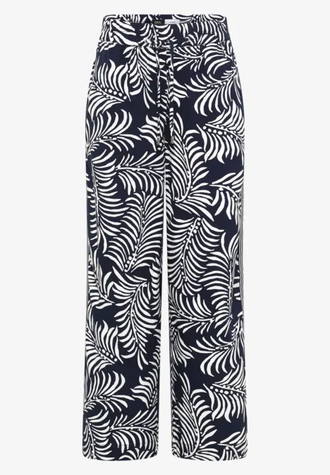 Wijde broek met donkere achtergrond en wit tropisch bladpatroon.