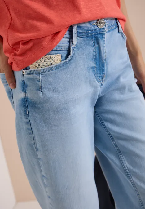 Frau trägt helle, locker sitzende Jeans mit gemustertem Einstecktuch in der Tasche und rotem Shirt.