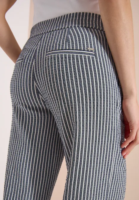 Achteraanzicht van een persoon in strak grijs-wit gestreepte broek.