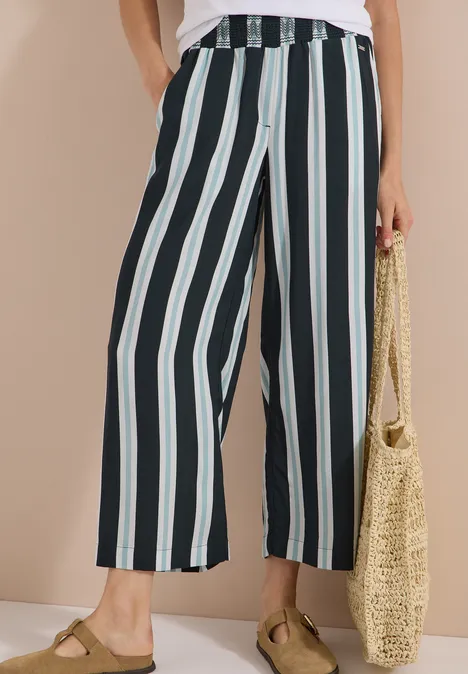 Pantalon taille haute à jambes larges à rayures palm breeze green Culotte à rayures verticales noir, blanc et menthe, accessoirisée d’un sac en paille et sandales