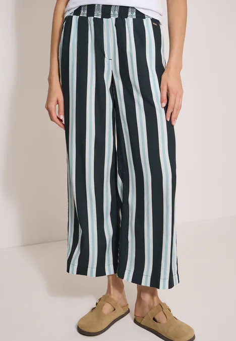 Pantalon taille haute à jambes larges à rayures palm breeze green Pantalon fluide mi-long à rayures verticales claires et foncées, porté avec des sandales.
