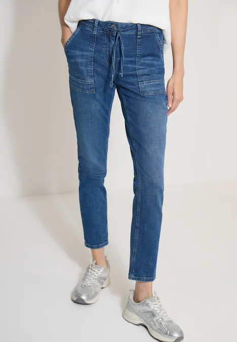 Blaue Denim-Jogginghose mit Kordelzug und aufgesetzten Taschen, kombiniert mit silbernen Sneakern.