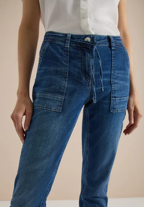 Frau trägt hellblaues Hemd und lässige Jeans mit aufgesetzten Taschen.