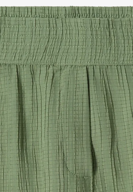 Grüner Rock mit elastischem Bund, feinen Falten und leicht gecrinkelter, strukturierter Baumwolloptik.