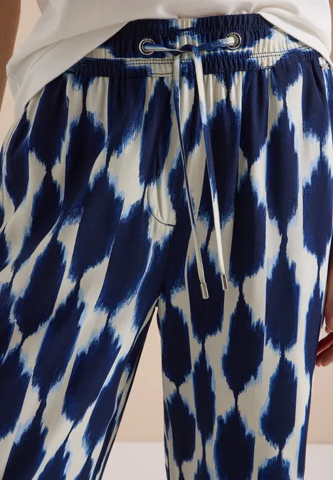 Locker geschnittene Hose mit blau-weißem abstraktem Muster und Tunnelzugbund.