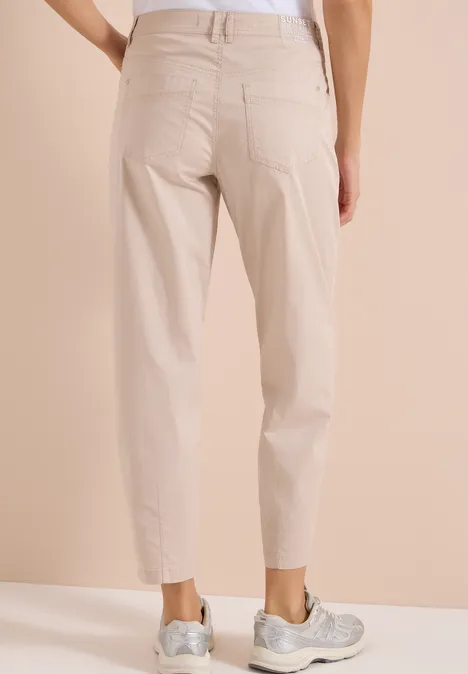 Spodnie z szerokimi nogawkami z tkaniny o fakturze papieru cashmere beige Beżowe spodnie o prostym kroju z podwiniętymi nogawkami, tylnymi kieszeniami i szarymi trampkami.