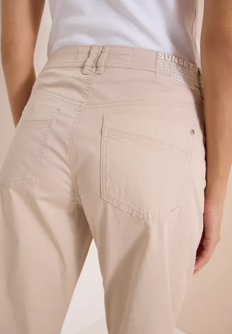 Spodnie z szerokimi nogawkami z tkaniny o fakturze papieru cashmere beige Tylny widok osoby w jasnobeżowych, dopasowanych spodniach i białej bluzce na jasnym tle.