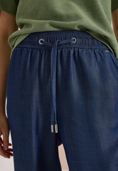 Eine Nahaufnahme zeigt eine Person mit blauer Hose mit Tunnelzug und grünem T-Shirt.