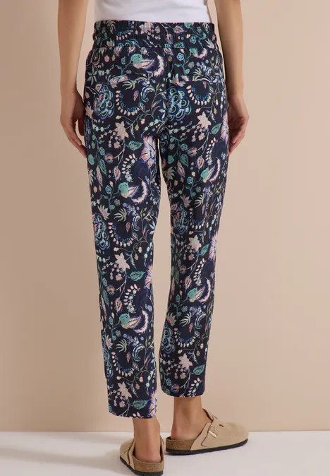 Rückenansicht einer Frau in einer dunkelblauen 7/8-Hose mit Blumen- und Paisley-Muster und elastischem Bund.
