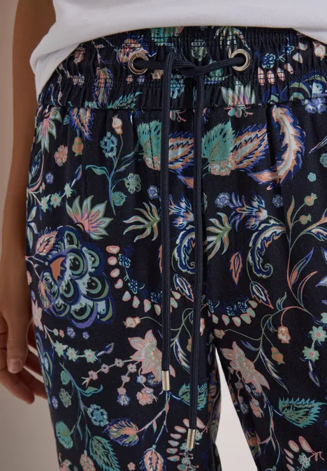 Hose aus dunkelblauem Stoff mit buntem Paisley- und Blumenmuster und Kordelzug.