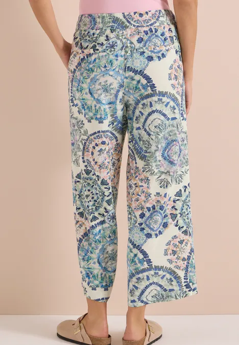 High Waist Wide Leg Hose w kroju Loose Fit vanilla white Kobieta w luźnych, szerokich spodniach z niebiesko-zielonym wzorem mozaiki.