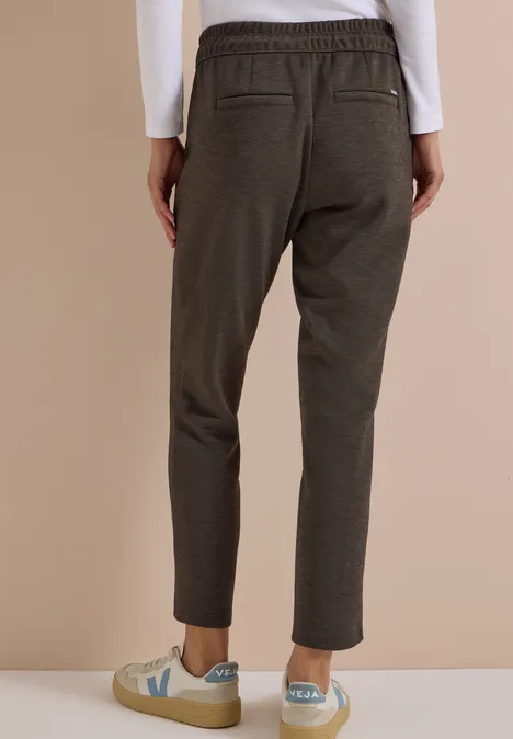 Pantalon taille mi-haute, coupe Slim Leg et style décontracté creamy mocha Rückansicht einer Person in olivgrünen, taillierten Hosen mit Gummibund und hellen Sneakers.