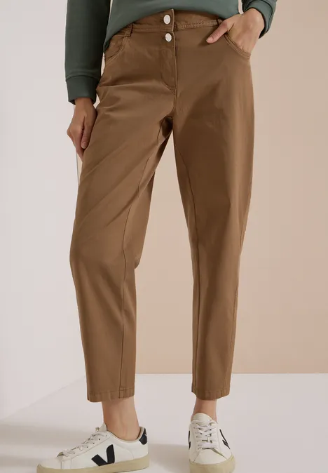 Mid Waist Barrel Leg Hose im Casual Fit creamy mocha Person trägt braune, hoch taillierte, plissierte Hose bis zum Knöchel und weiße Sneaker.
